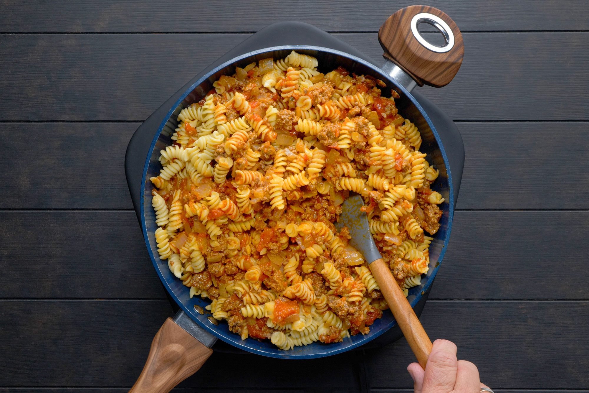 Stiring in spaghetti sauce and pasta in a skillet