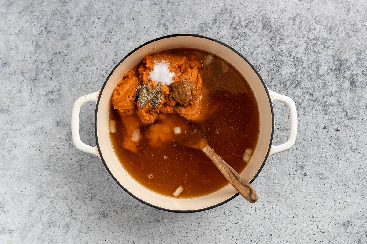Taste of Home Pumpkin Bisque recipe photo of the broth, pumpkin, salt, pepper, nutmeg added to the dutch oven.