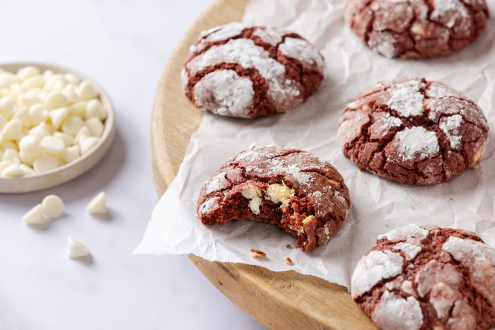 Red velvet crinkle cookies served on wooden board layered with parchement paper.