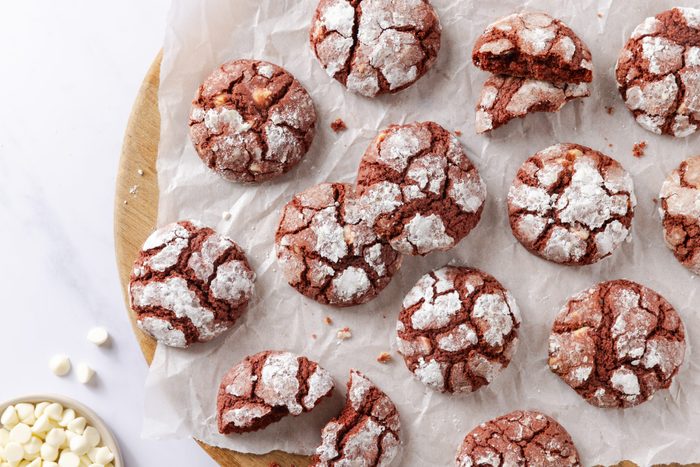 Red velvet crinkle cookies served on wooden board layered with parchement paper.