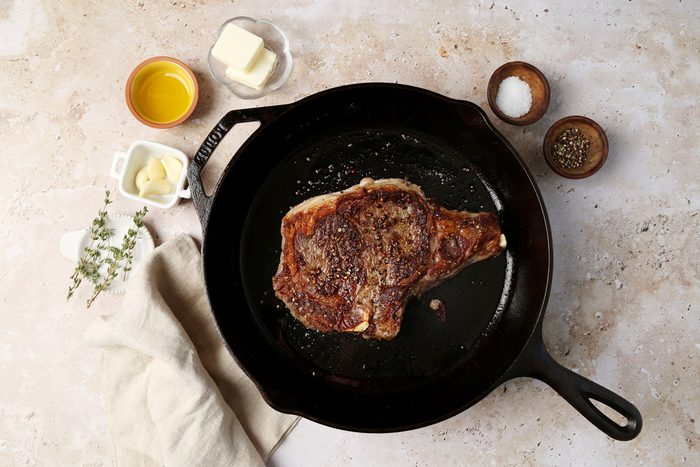 A how to look into Taste of Home's homemade Steak Frites. Steak in a cast iron pan with butter, garlic and thyme.