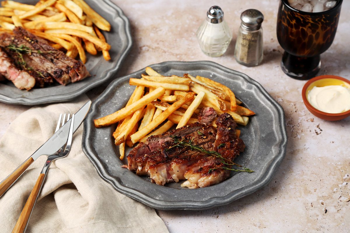 Taste of Home's homemade Steak Frites served on silver plates.