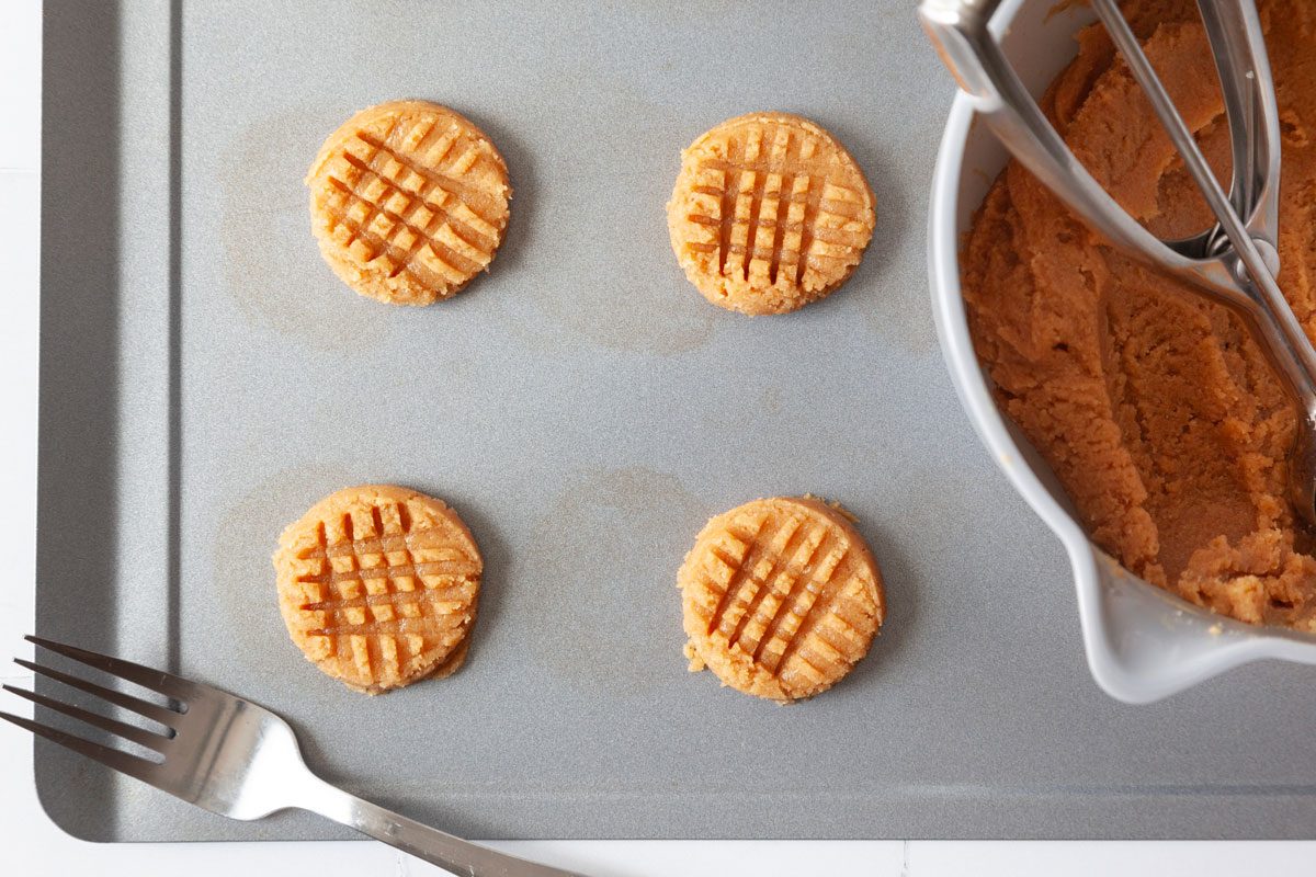 Step 1 of Taste of Home 3-Ingredient Peanut Butter Cookies is to mix all of the ingredients together. Scoop out level tablespoonfuls of the batter and roll them into balls. Place these on ungreased baking sheets and flatten them with a fork, pressing down in perpendicular lines to make a lovely lattice pattern on the cookies.