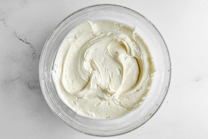 Buttercream for Taste of Home Amaretto Cake in a glass bowl on a marble surface