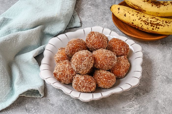 A bowl of banana beignets with bananas in the background.