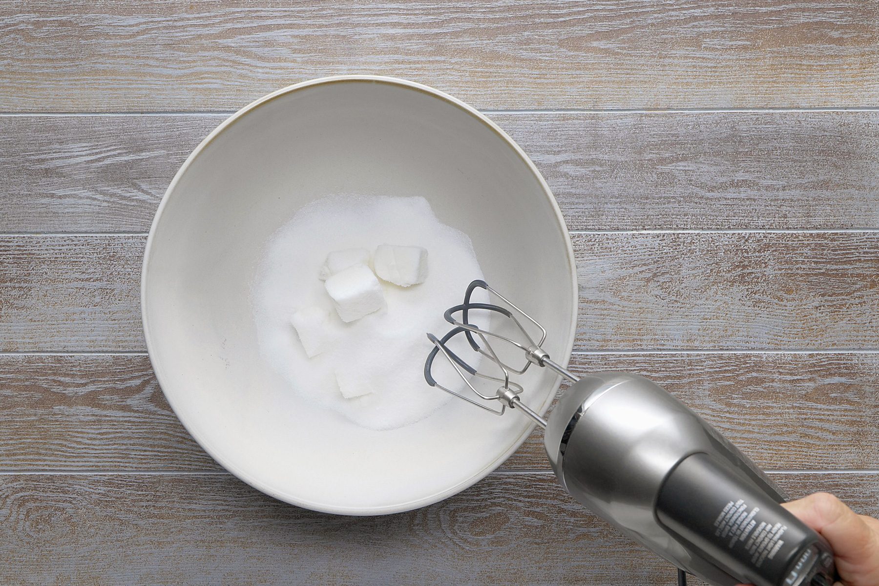 overhead shot; grey background; In a large bowl, cream shortening and sugar along with electric whisker