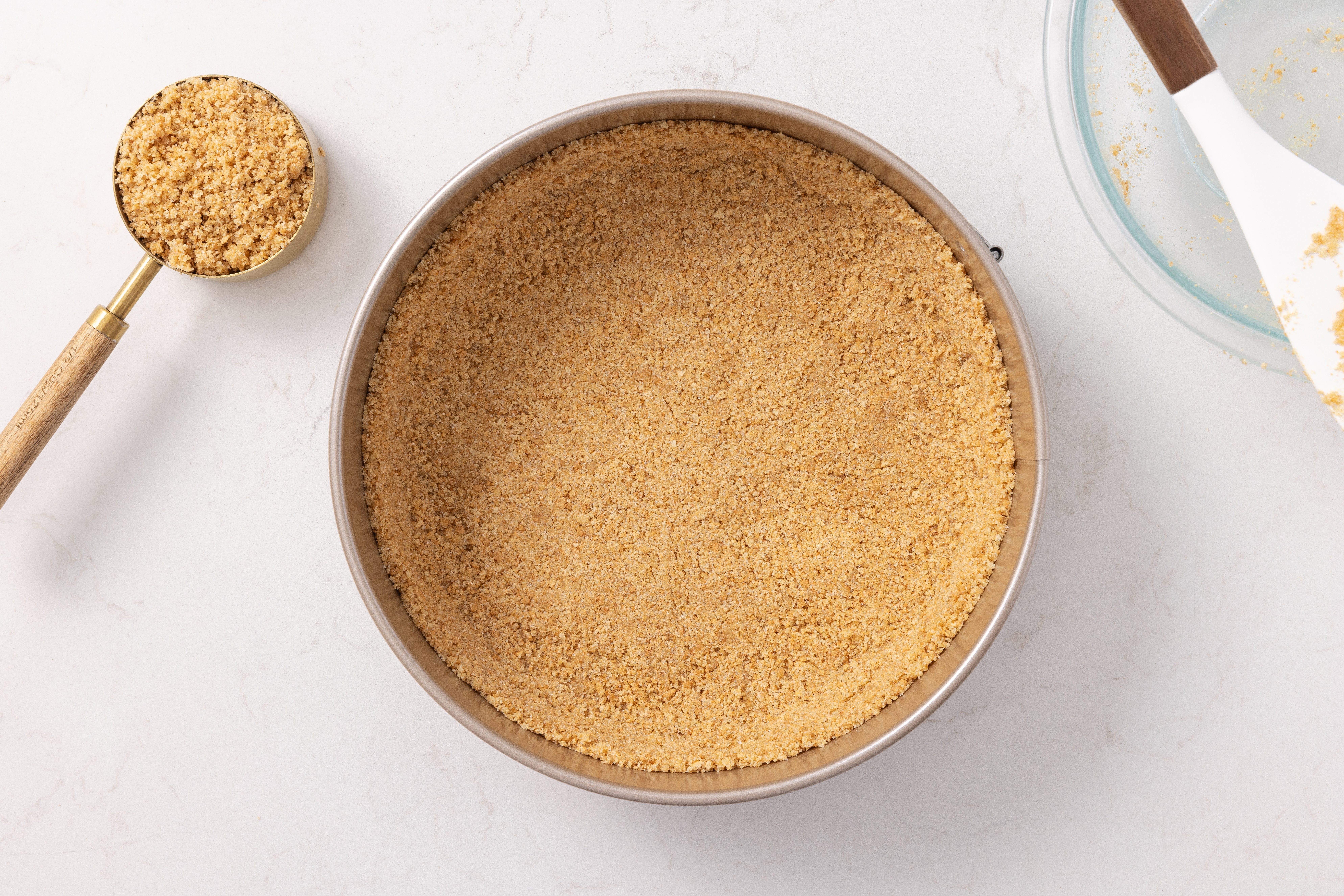 Cheesecake crust being pressed onto springform pan.