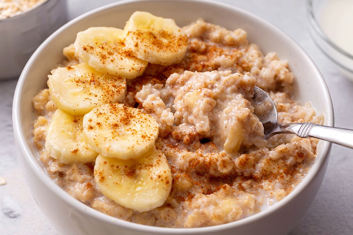 Banana oatmeal topped with sliced banana and cinnamon in a bowl with a scoop being taken out