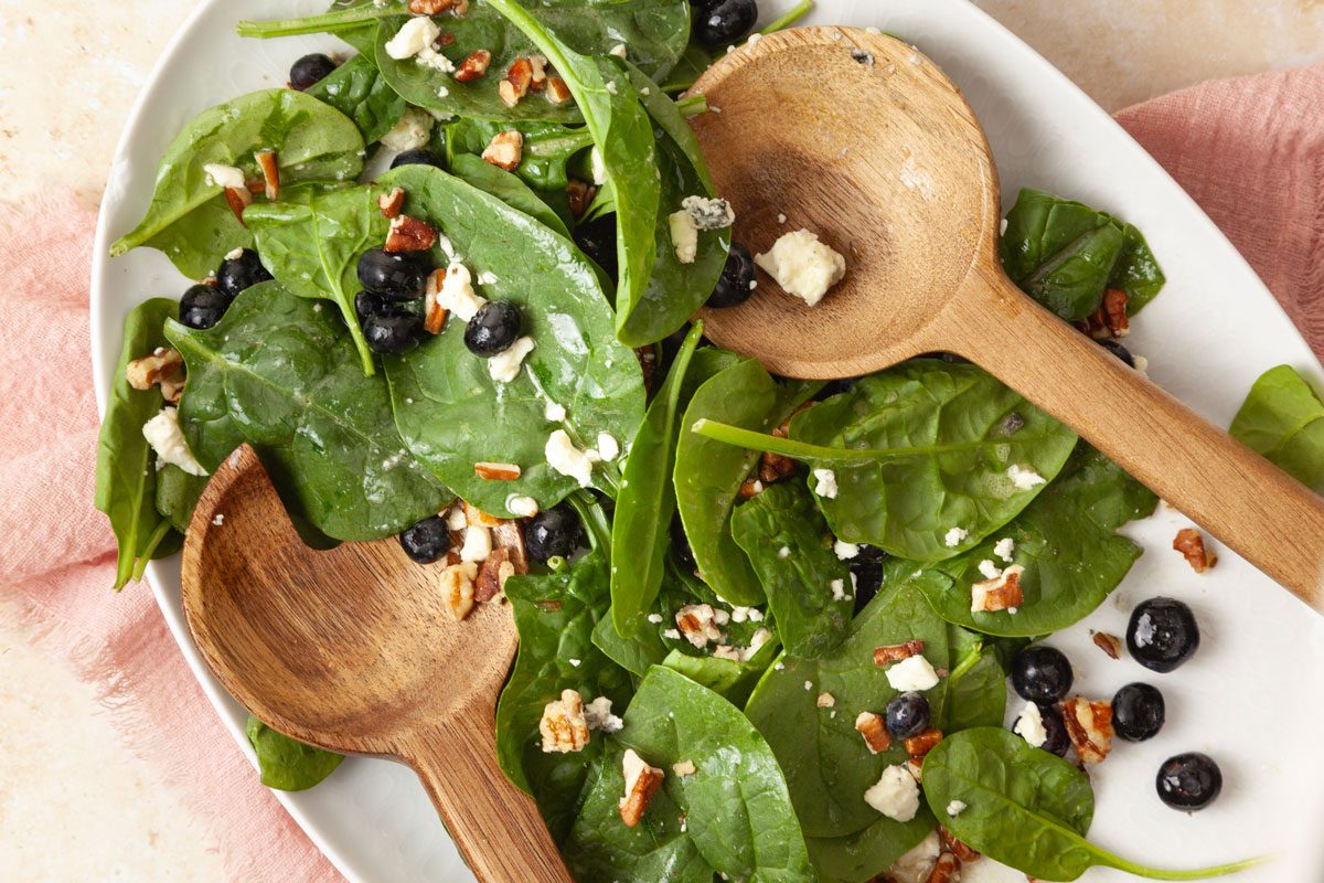 Full yield of Taste of Home Blueberry Salad on a white oval serving platter, pink linen, wooden salad servers