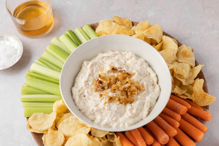 Caramelized onion dip served with fresh vegetables and potato chips.