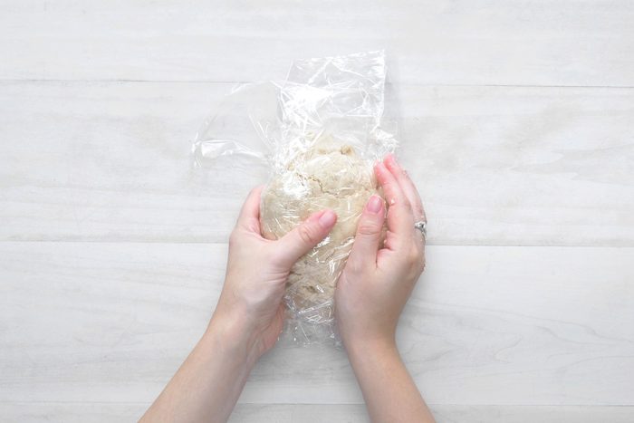 overhead shot; white wooden background; covered the dough with plastic wrap