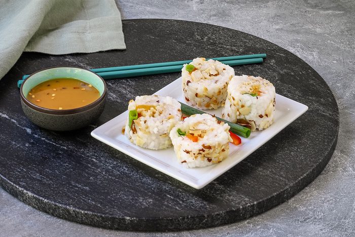 An appetizer plate with sliced chicken tempura roll and dip.