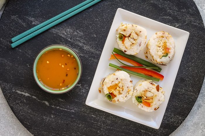 Chicken tempura roll slices on a plate with dip on the side.