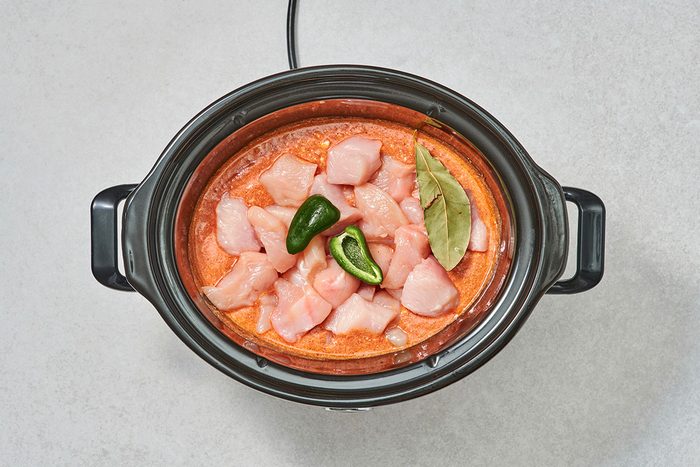 Cubed chicken jalapeño and bay leaf added to the sauce in a slow cooker