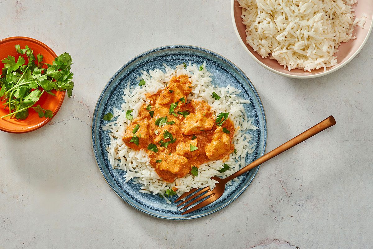 Chicken tikka masala served over basmati rice garnished with chopped cilantro