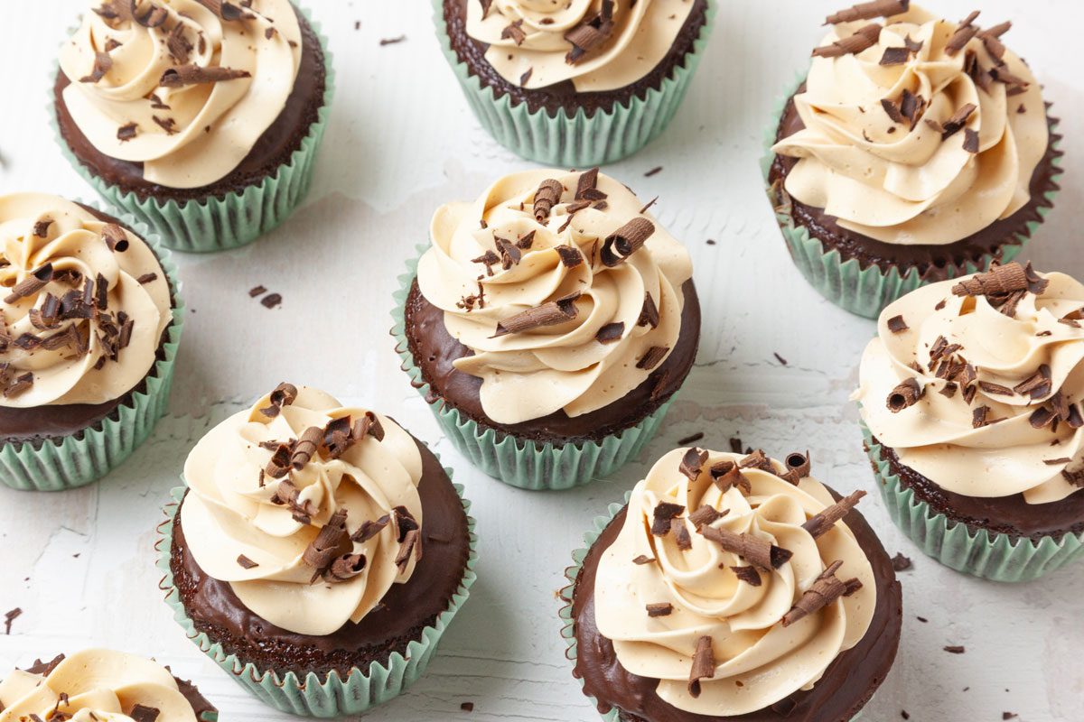 Taste of Home Chocolate Peanut Butter Cupcakes in light aqua liners, garnished with chocolate curls, on surface