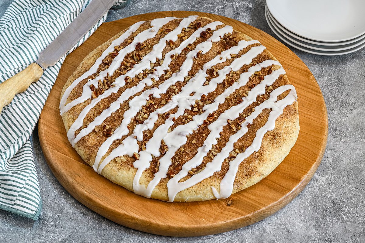 Glazed cinnamon roll focaccia on a cutting board, ready to enjoy.