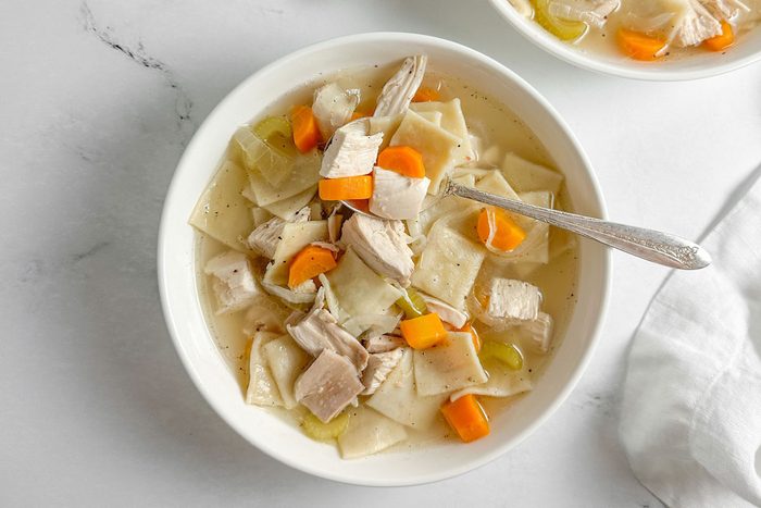 Taste of Home Copycat Cracker Barrel Chicken and Dumplings in white bowls on a marble surface