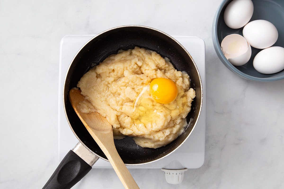 Eggs being mixed with cream puff dough for step one of Cream Puff Cake recipe for Taste of Home