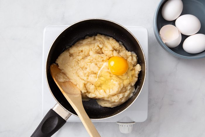 Eggs being mixed with cream puff dough for step one of Cream Puff Cake recipe for Taste of Home