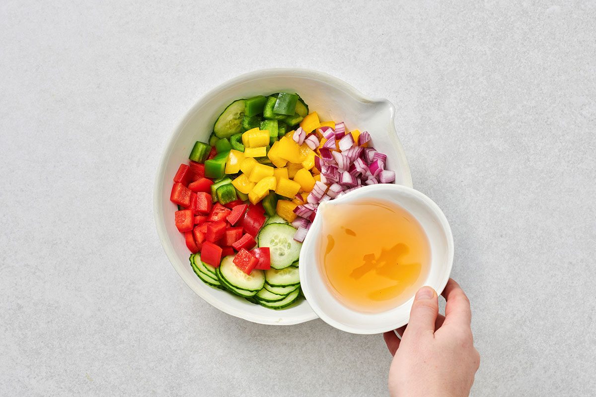 Pouring dressing over the unmixed salad ingredients
