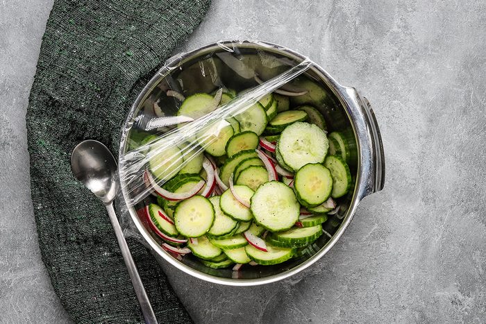 Sliced cucumbers and red onions in a bowl with a vinegar and sesame oil dressing.