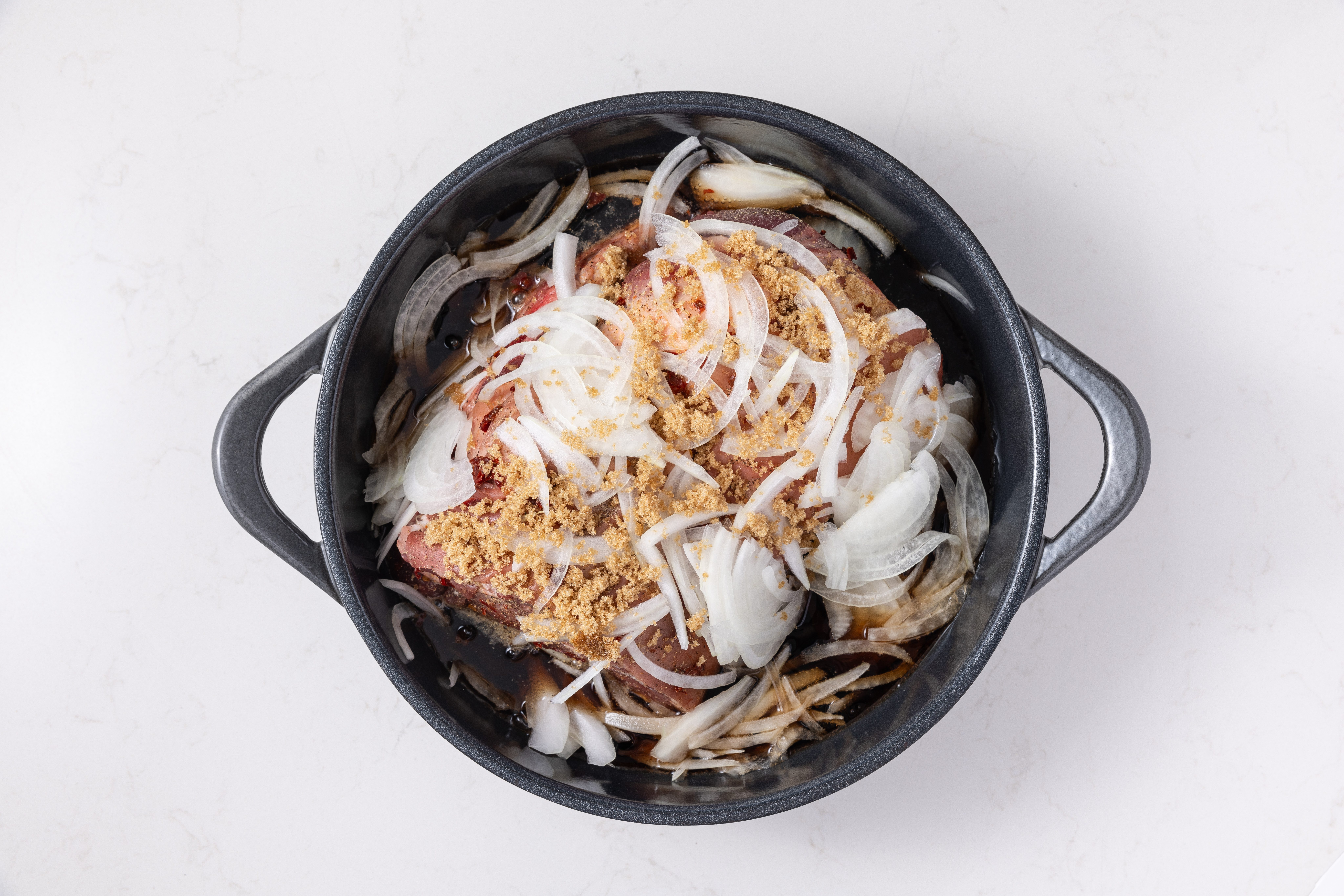 Pork roast in dutch oven with onions, dr pepper and brown sugar.