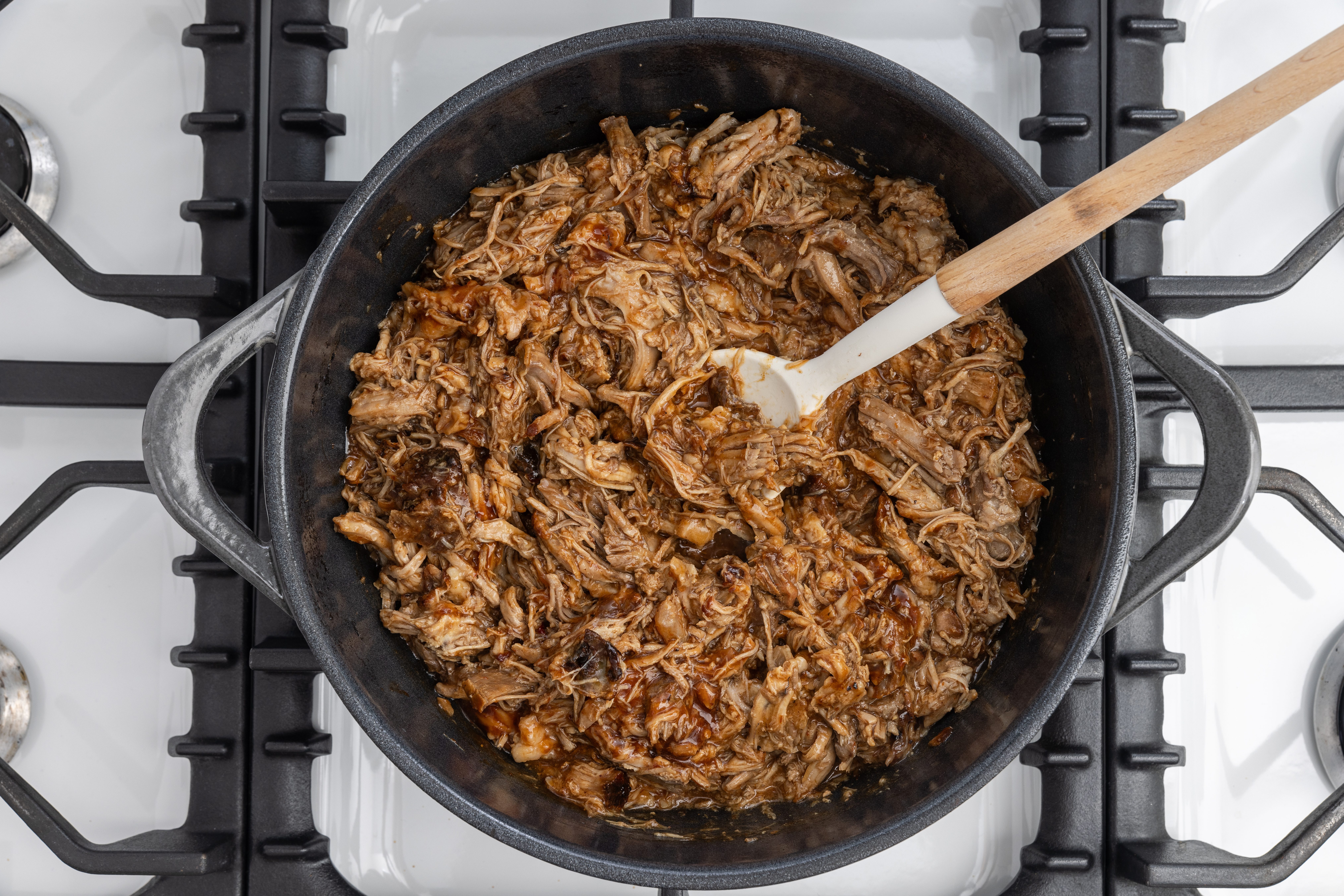 Pork meat shredded and finalized with barbecue sauce in dutch oven.