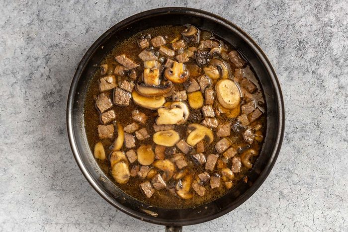 Taste of Home Easy Beef and Noodle recipe photo of the sauteed onion and mushroom, beef, and broth in a skillet.
