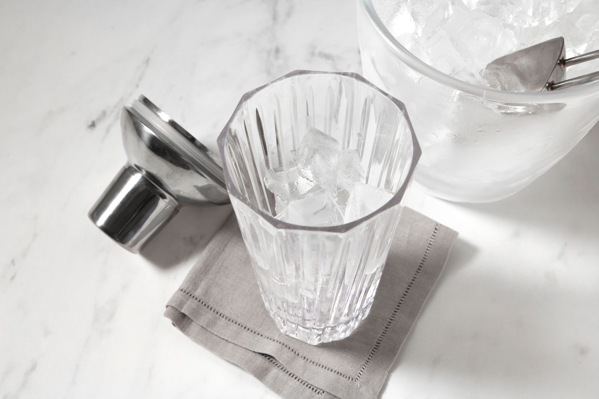 A clear glass tumbler filled with ice cubes