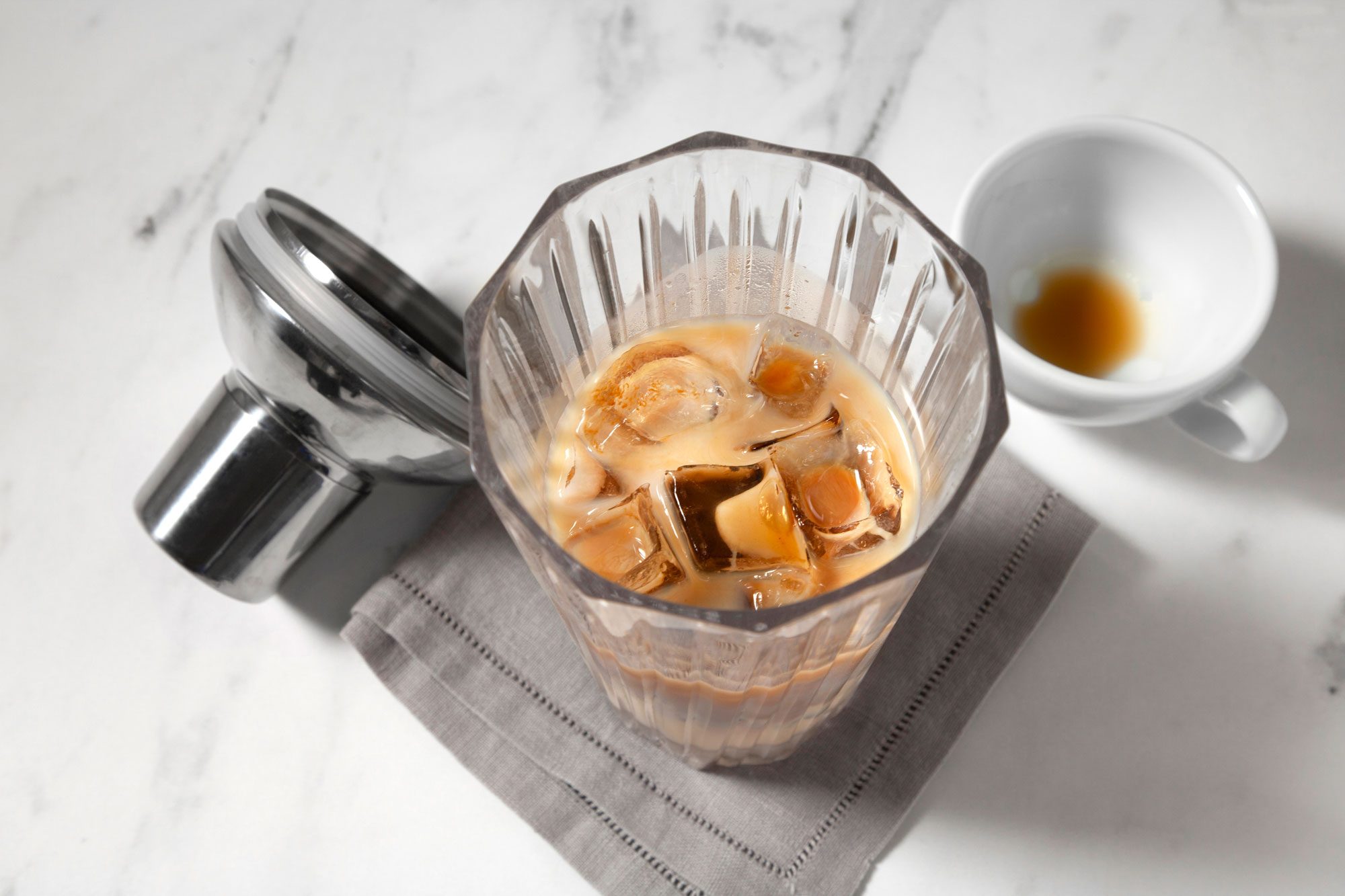 A glass tumbler filled with ice cubes and a creamy, brown liquid