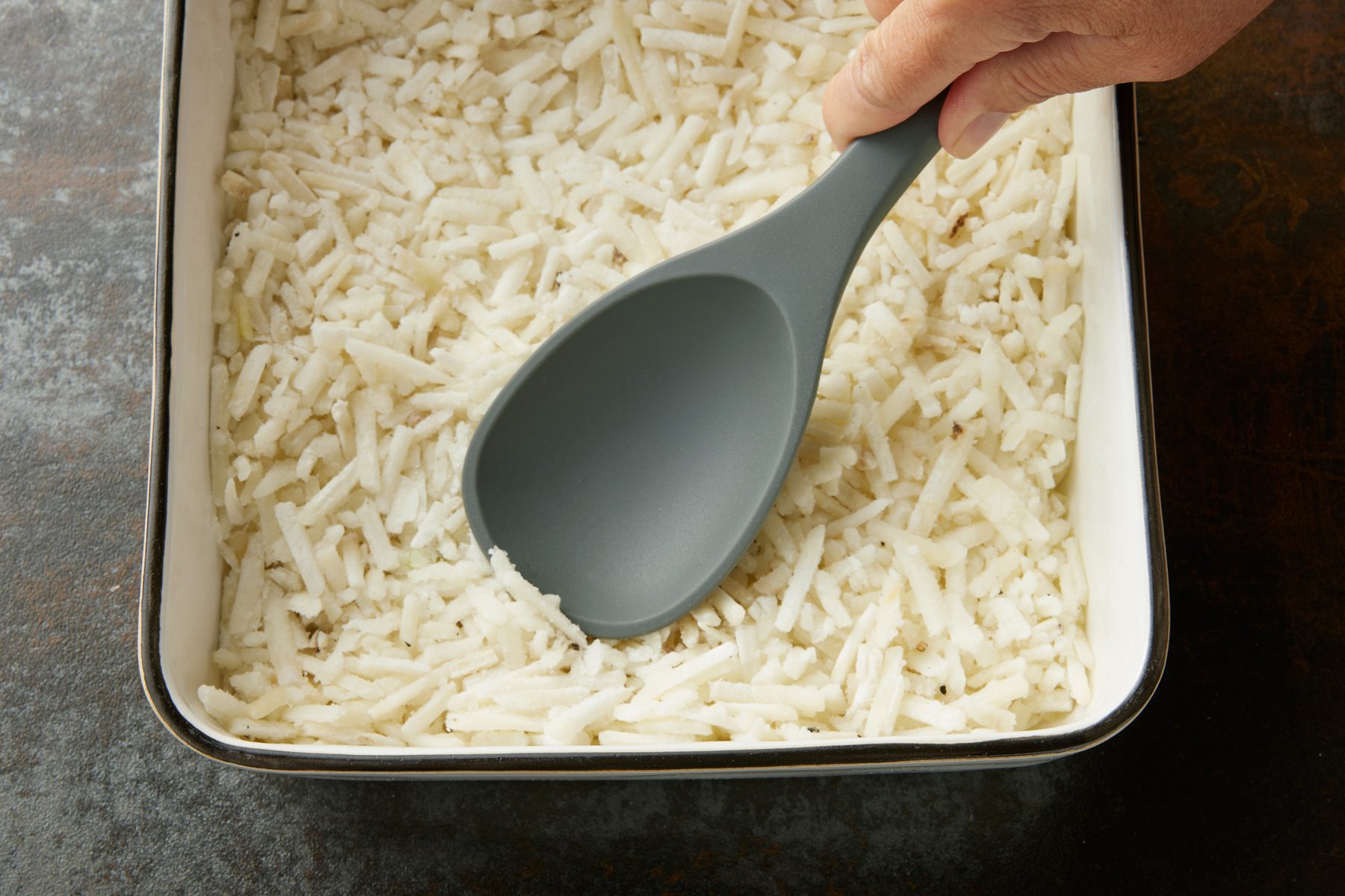 Overhead shot of press into a greased square baking dish; bake; uncovered until potatoes are thawed and set; spoon; dark texture surface