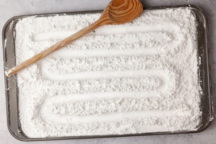 Step 1 of Taste of Home Hard Candy is to fill a 15x10x1-inch baking pan with confectioners' sugar to a depth of 1/2 inch. Using the handle of a wooden spoon, drag it through the sugar to make a continuous curved-line indentation in the sugar