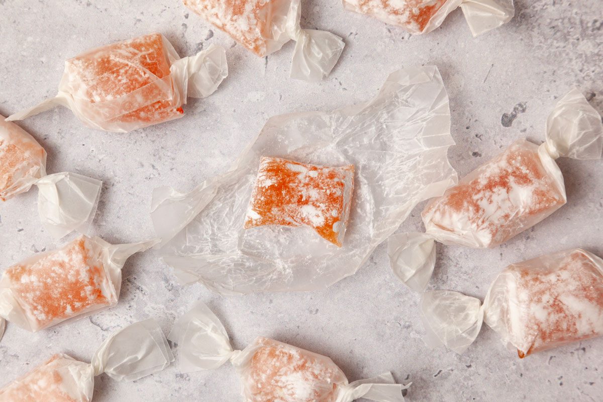 A few pieces of Taste of Home Hard Candy wrapped in wax paper, scattered on the surface, one wrapper open