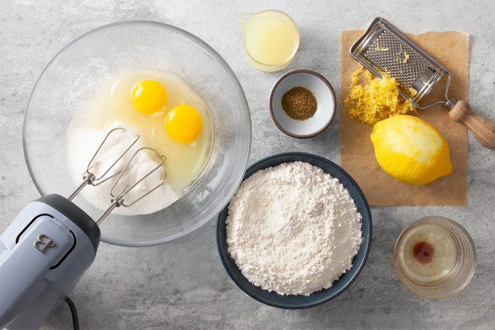Overhead shot of all ingredients; in a small bowl beat eggs and sugar until thickened; add oil and extracts; mix well; blender; grey marble surface;
