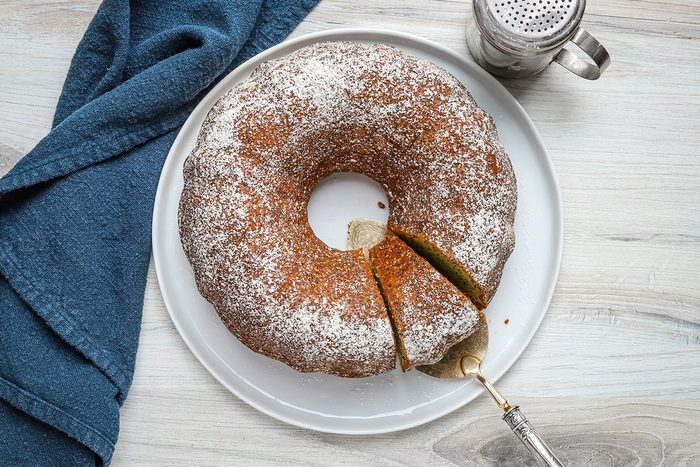 Overhead view of a lemon poppy seed cake with a slice being removed.