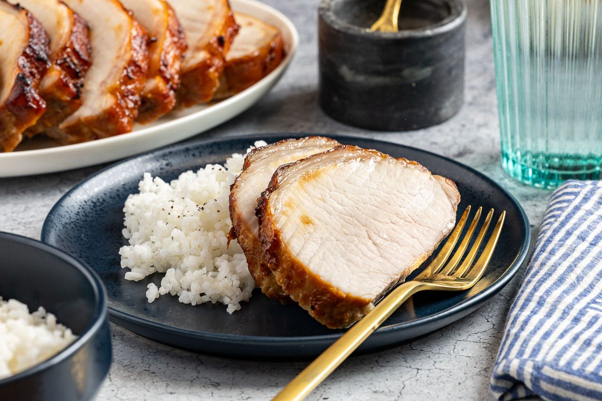Taste of Home Marinated Pork Loin photo of the finished recipe cut into slices and served on plates with a side of rice.