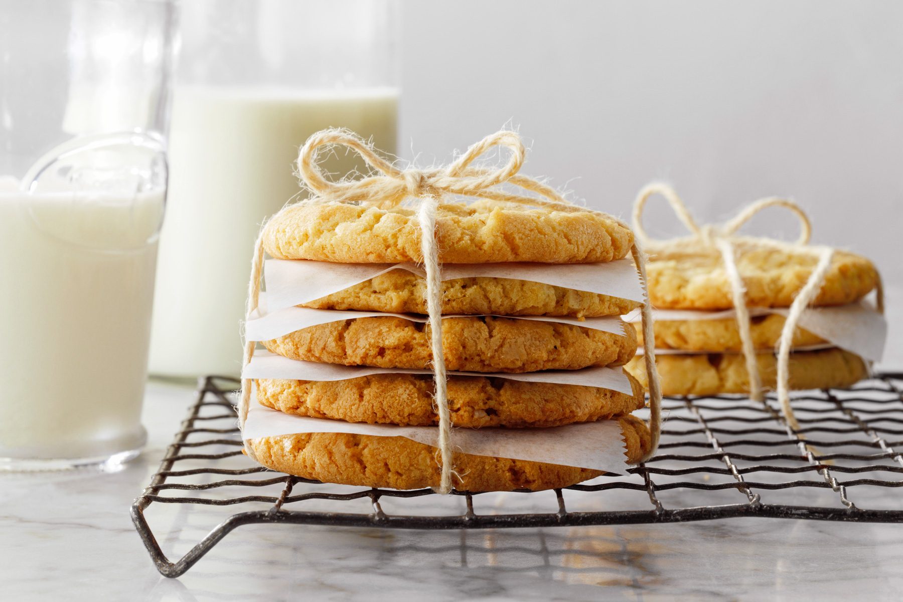 Oatmeal Coconut Cookies tied with thread on wire rack, milk on the side