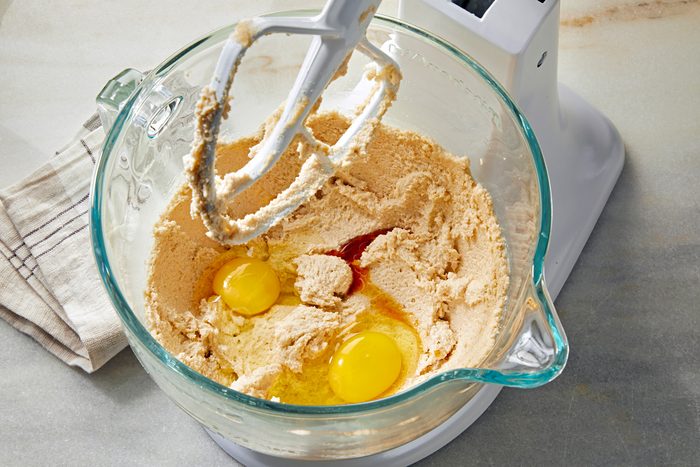 Top view shot of mixing eggs and vanilla extract in large bowl
