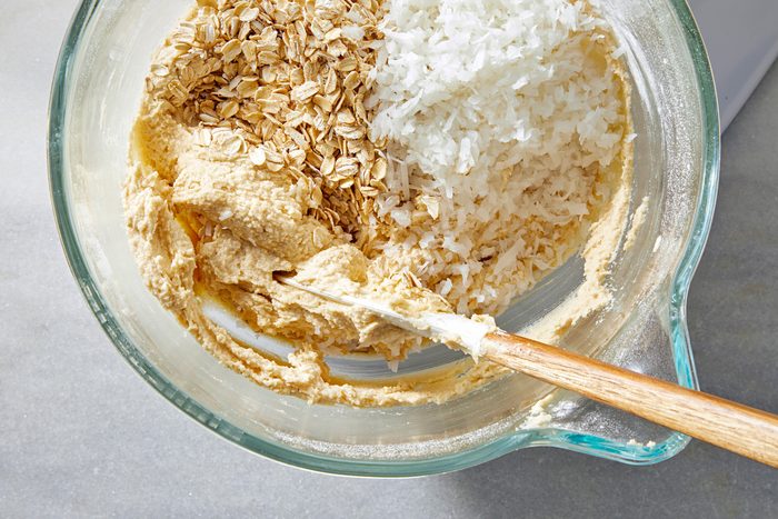 Top view shot of adding coconut and oatmeal to the mixture