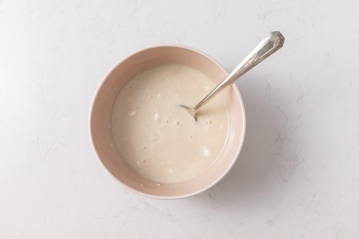 Glaze for cinnamon rolls being mixed in small bowl.