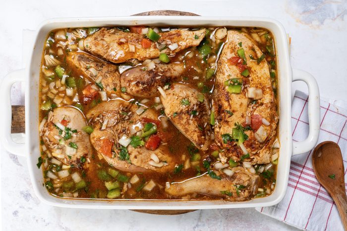 Placing the chicken pieces on top of the rice and stock