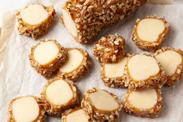 Close up of full yield of Taste of Home Pecan Logs cut into slices on a round wooden cutting board with parchment paper