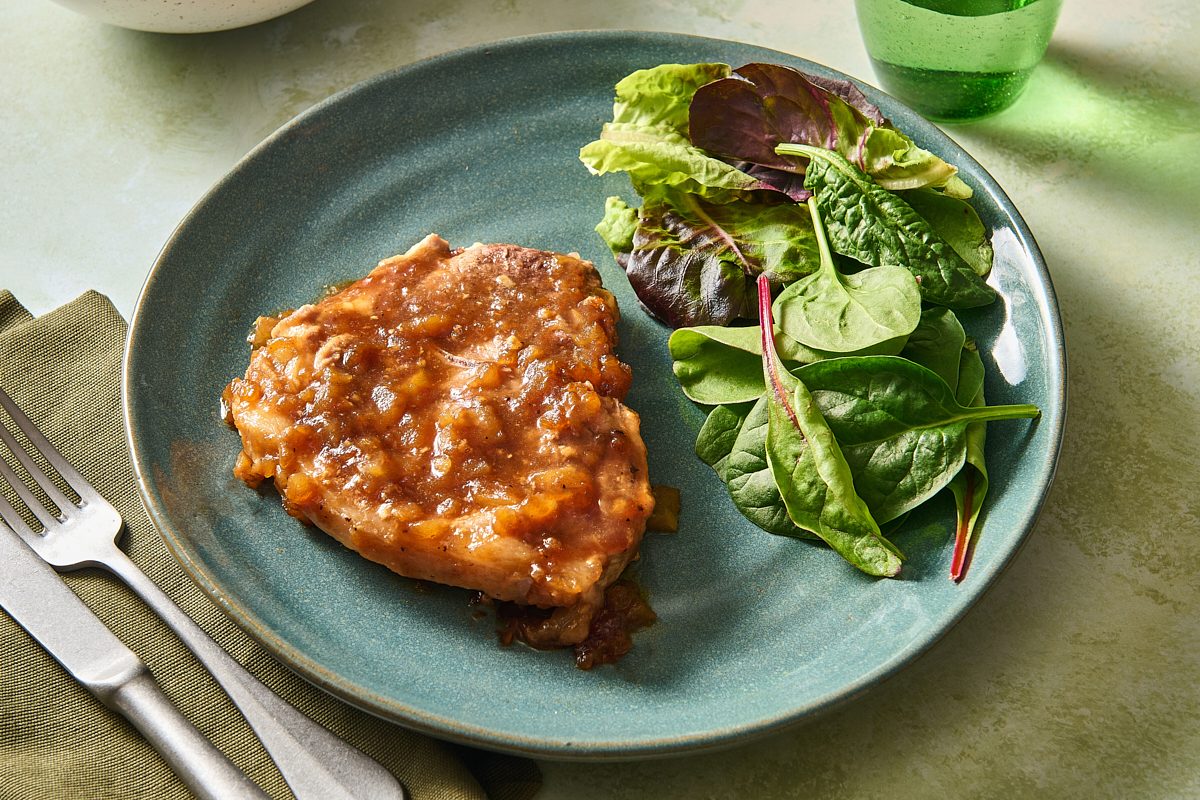 Closeup shot of a pork chop topped with applesauce