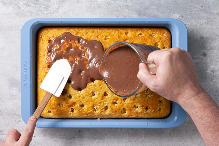 Overhead shot of a small bowl whisk milk and pudding mix 2 minutes; immediately spread into holes and over top of cake; refrigerate 30 minutes; spatula; grey surface