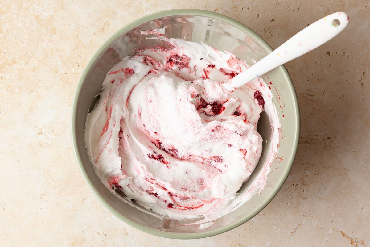 Step 3 of Taste of Home Raspberry Cake is to gently fold the thawed whipped topping into the thawed raspberries until well combined. Once the cake is at room temperature spread the frosting evenly over it.