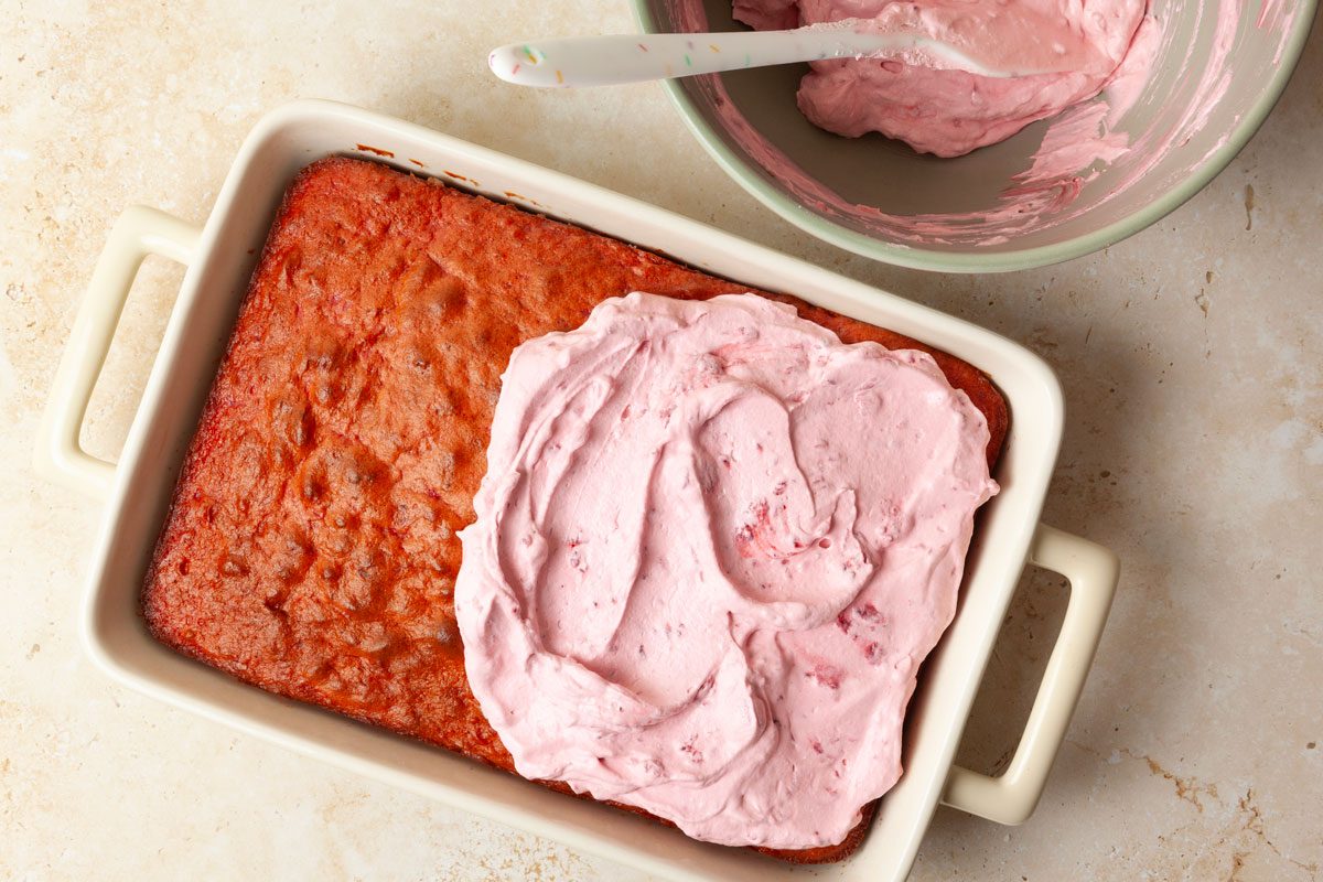 Step 4 of Taste of Home Raspberry Cake is to spread the frosting evenly over it.Â