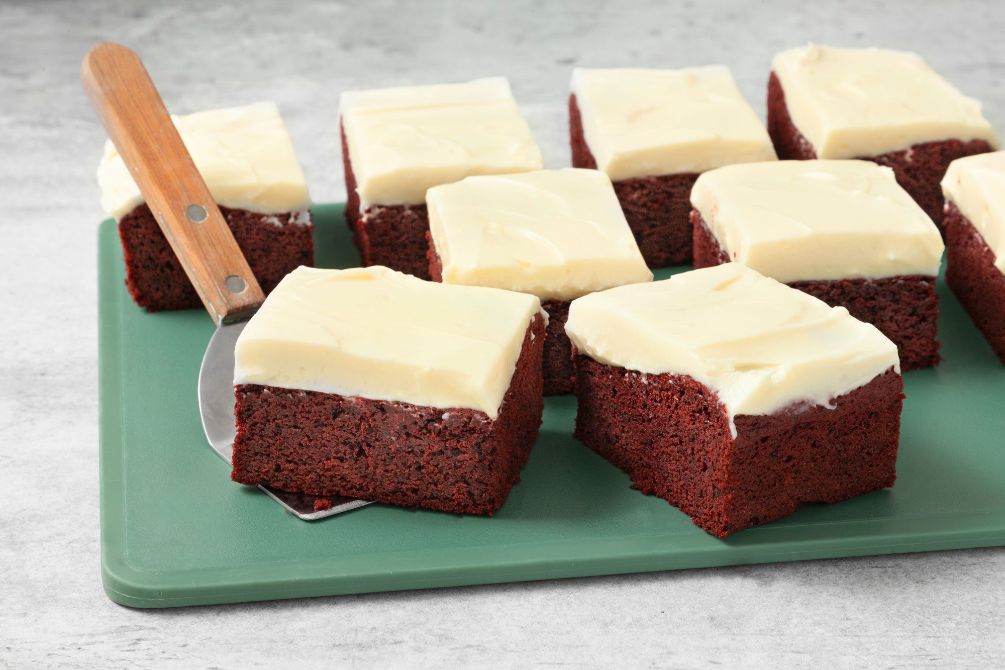 Red Velvet Brownies with Cream Cheese Frosting on a chopping board