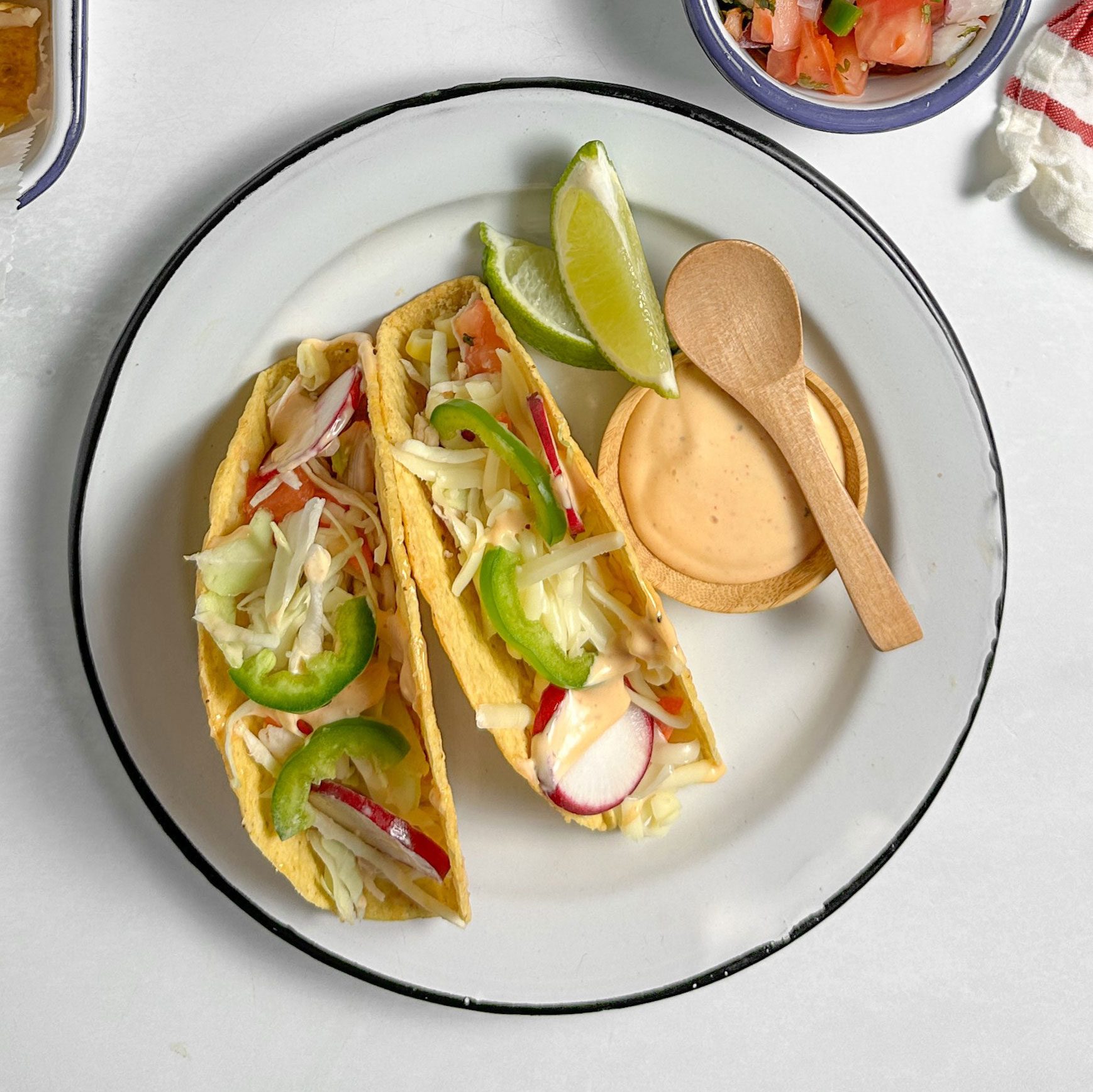 Taste of Home Shredded Chicken Tacos with assorted toppings on enamel dishes