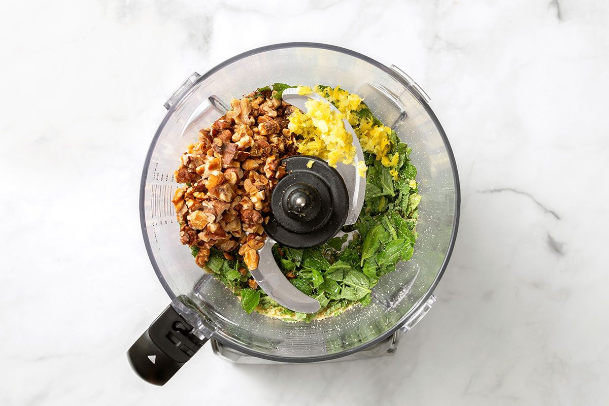 Chopped baby spinach, basil leaves, romano cheese with roasted walnuts, lemon zest and juice in a food processor for Spinach Pesto for Taste of Home